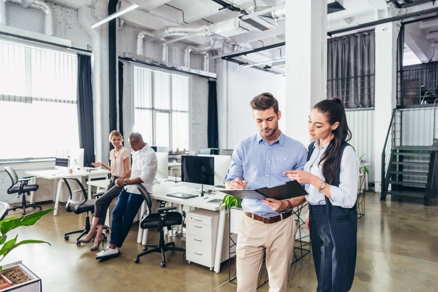 Four people talking in an office. Two are looking at information in an open folder.