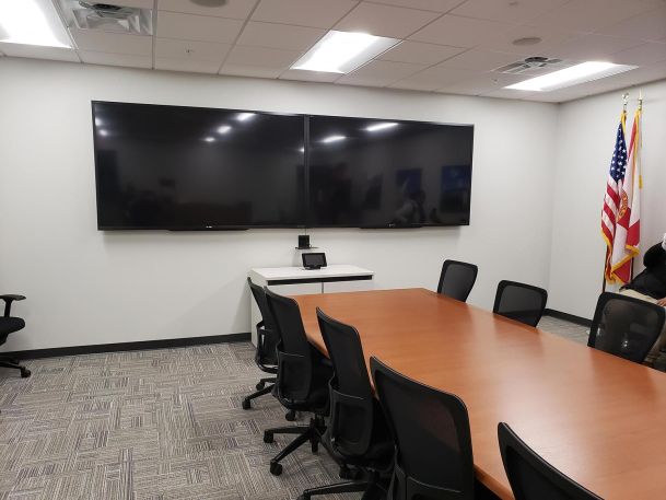 Government Conference room with a wood table and two large TVs